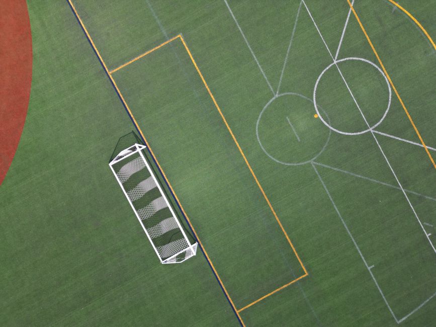 Top-down view of a vibrant, empty soccer field highlighting the goal net and pitch lines.